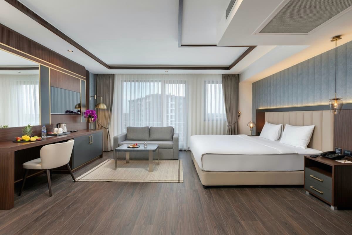 Deluxe Room with a king bed, a long writing desk, a sofa and floor-to-ceiling windows