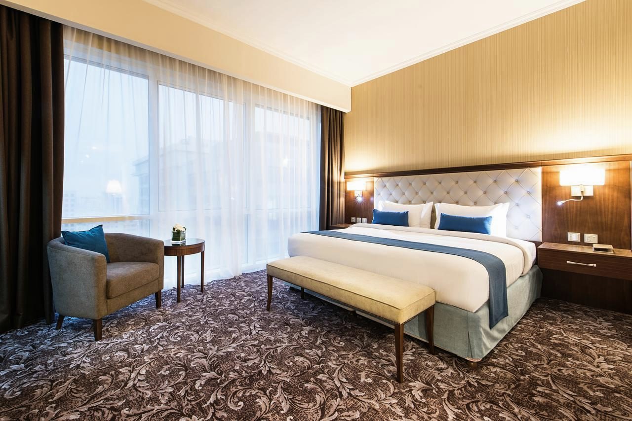 Executive Room with a king bed, a tufted headboard, an armchair and full-height windows